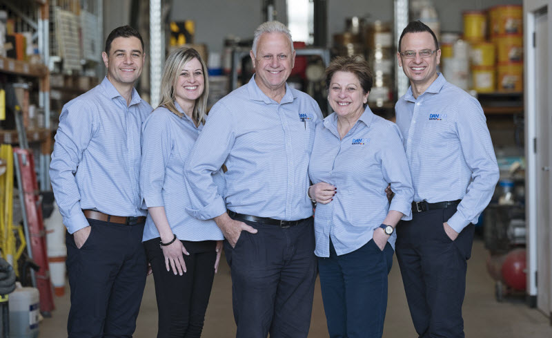 Team inside a warehouse smiling at the camera