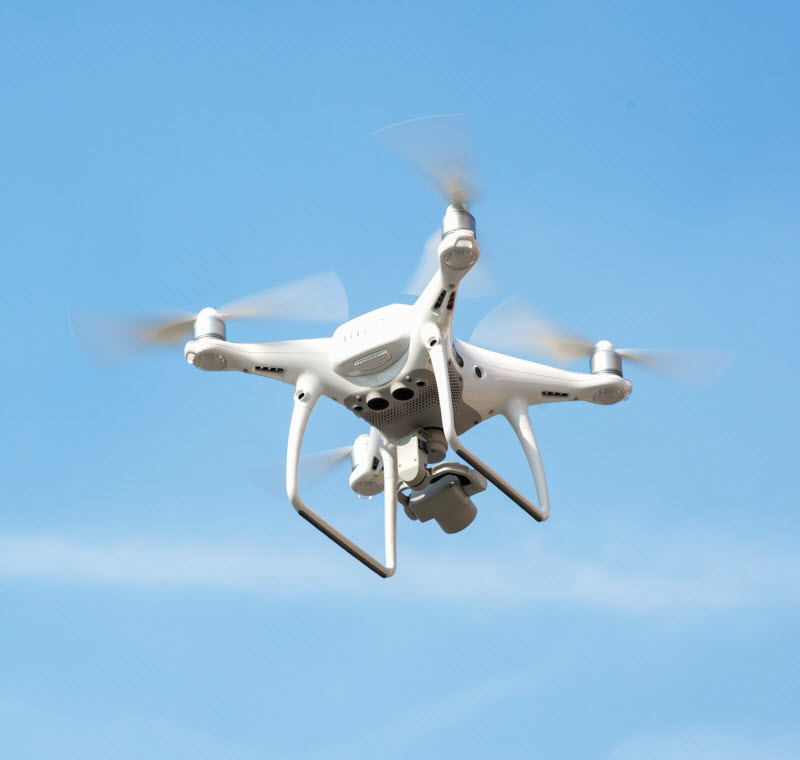 white drone hovering in a bright blue sky